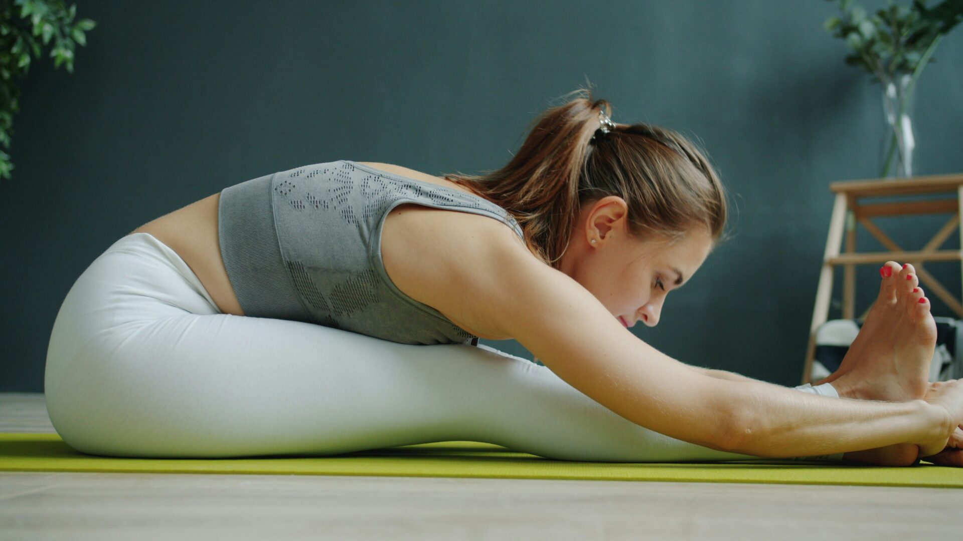 Woman performing seated forward fold on mat