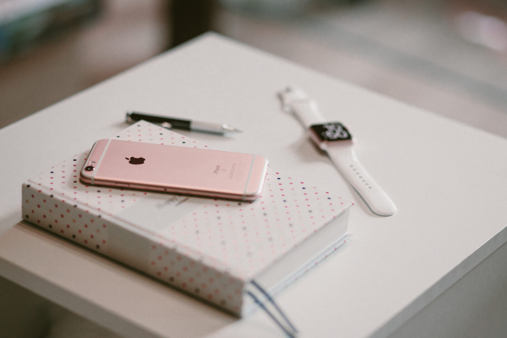 Pink smartphone on dotted notebook with smartwatch