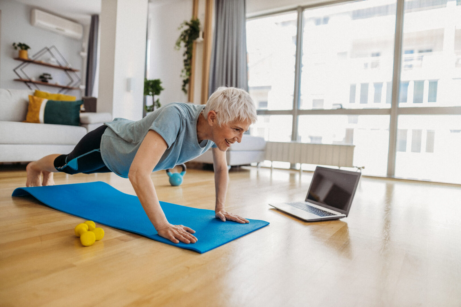 Senior woman exercising with laptop at home