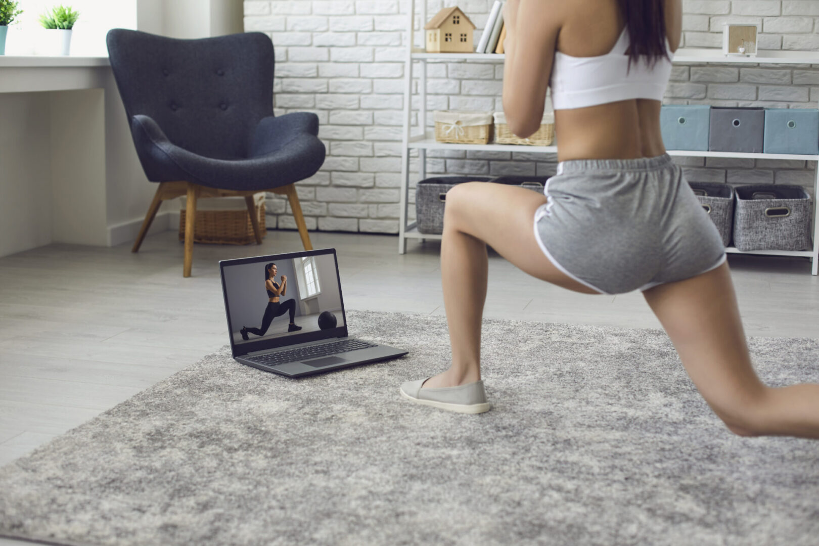 Online fitness at home. The girl does exercises watching the video course the trainer has a laptop at home. A young woman leads an active lifestyle is engaged in fitness remotely with a virtual trainer.