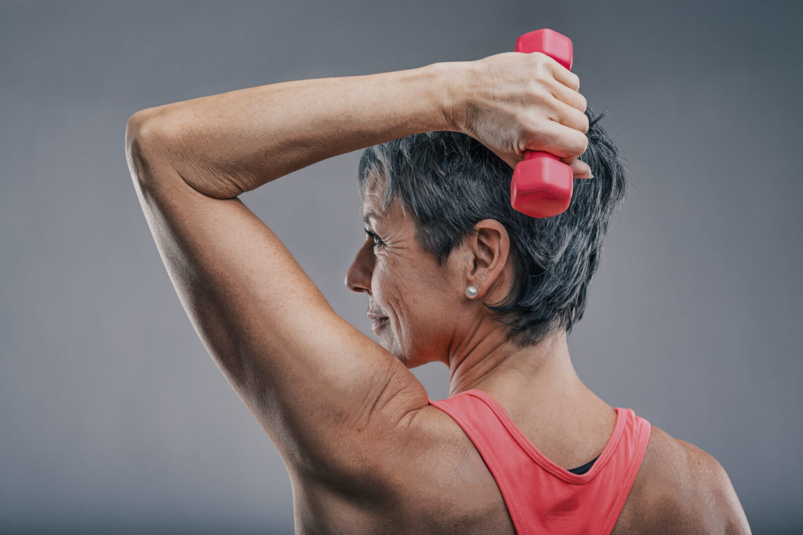 Woman lifting red dumbbell overhead