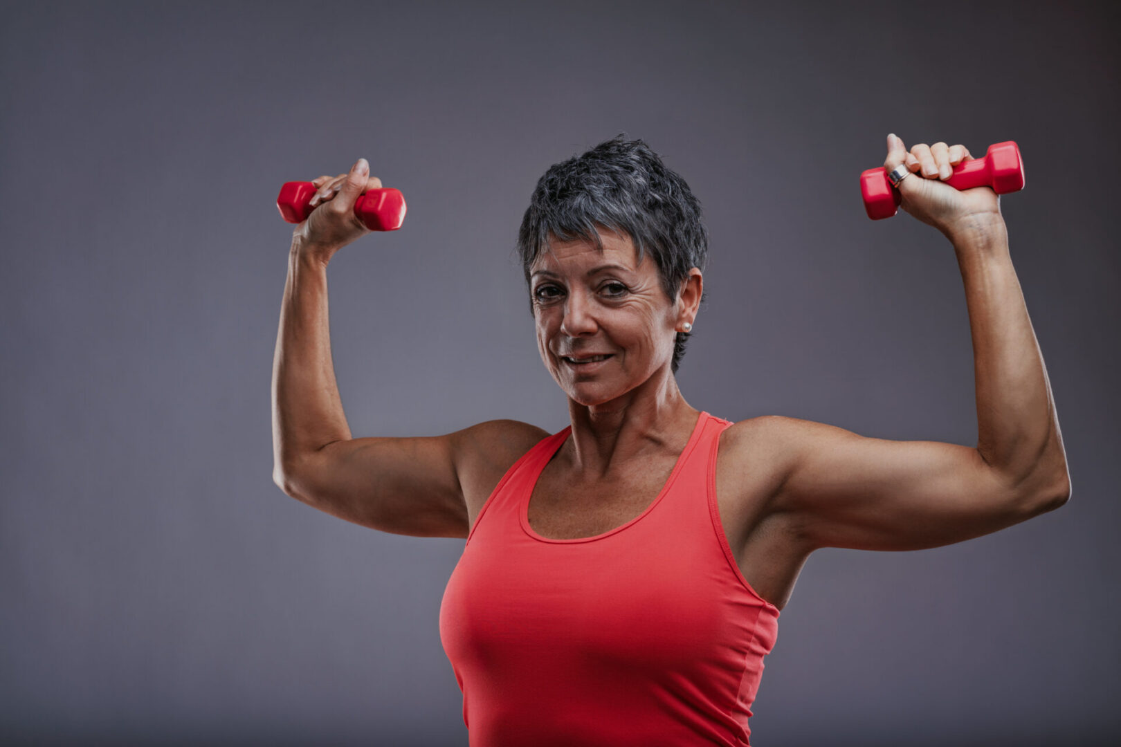 Mature woman exercising with red dumbbells