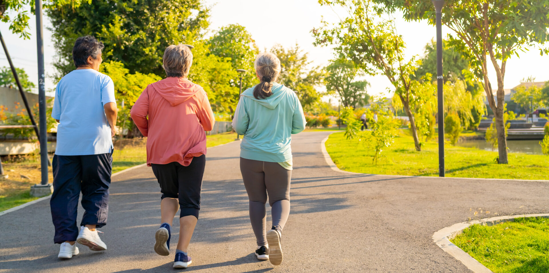 Three people jogging on sunny park path